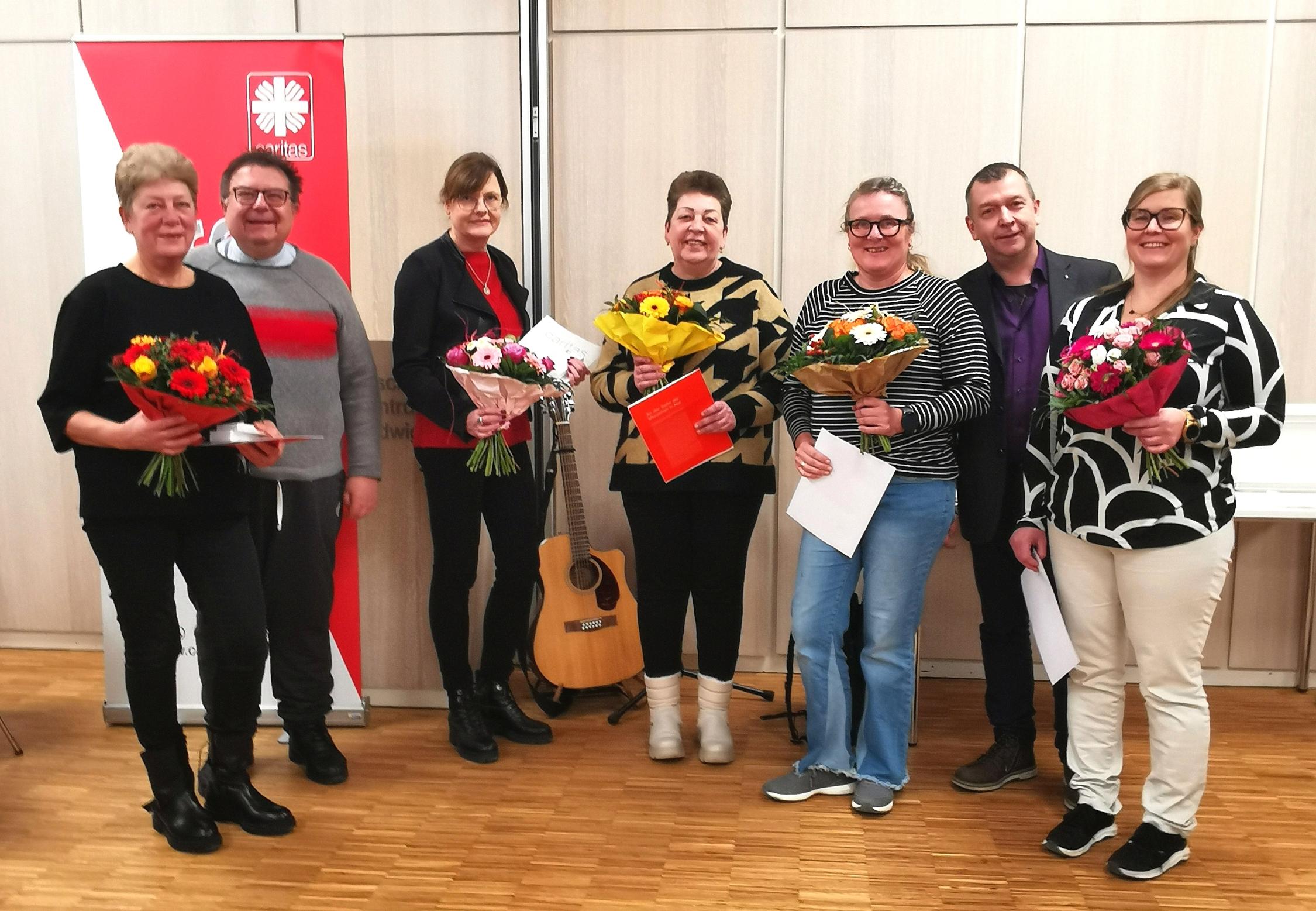 Gruppenfoto mit Blumen und Gitarre: Lili Herterle, Alla Merz, Vorstandsvorsitzender Hans-Peter Kunert, Brigitte Guggenberger, Karin Heinritz, Geschäftsführer Sebastian Grund und Marylin Krug (v.l.n.r.)